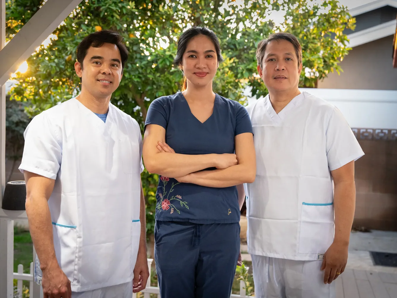 Three professional caregivers in medical scrubs standing together at residential care facility