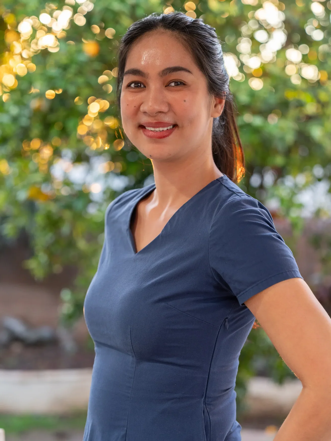 Smiling caregiver in navy medical scrubs standing outdoors